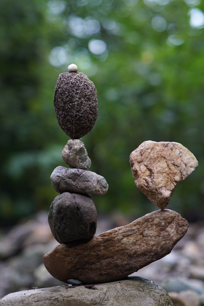 A creative display of balance with stacked stones against a blurred nature background.